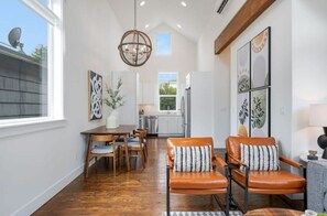 A spacious dining area with a wooden table and chairs, a chandelier, and artwork on the walls.