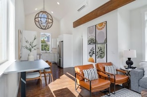 A modern living room with a dining area, a kitchen, and a large window.