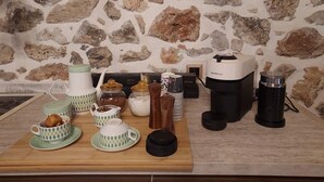 Un plan de travail de cuisine avec un mur en pierre en arrière-plan, divers appareils de cuisine et une machine à café.