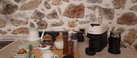 Een keukentafel met een achtergrond van een stenen muur, verschillende keukenapparaten en een koffiezetapparaat.