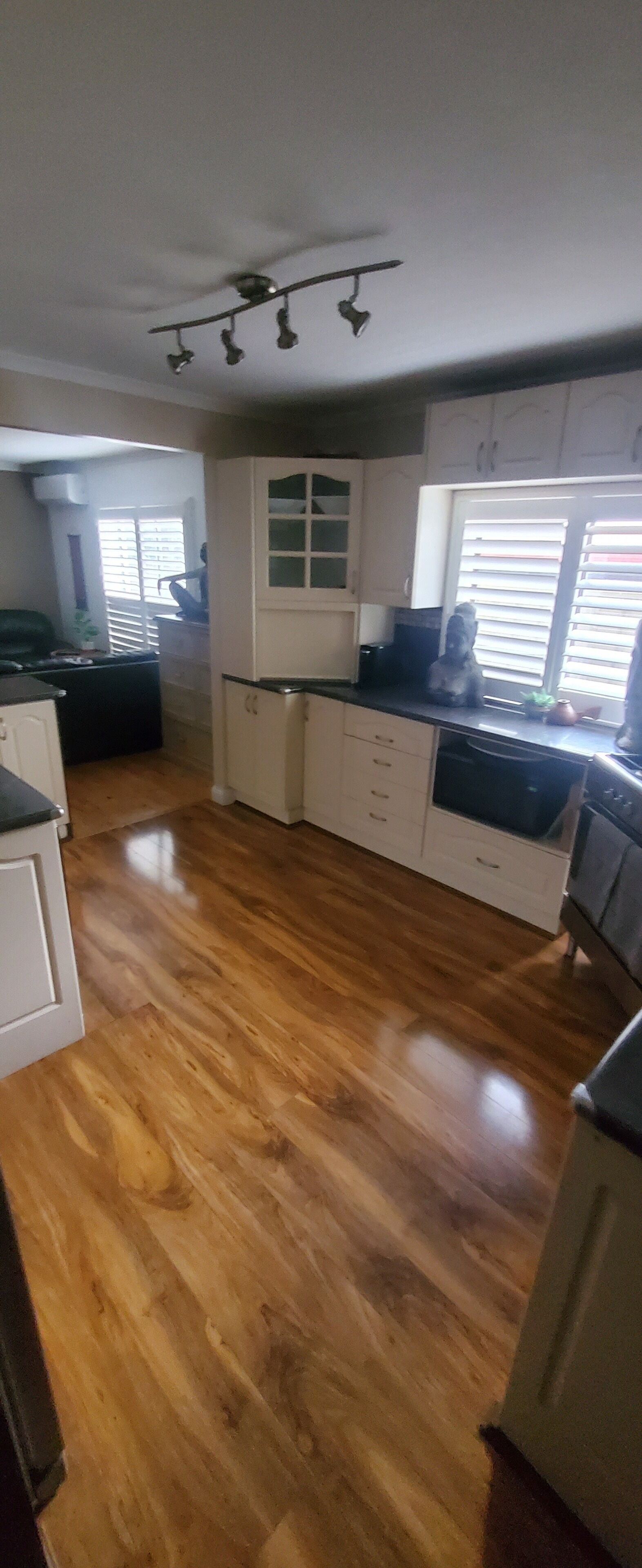 A kitchen with white cabinets, a black countertop, and a wooden floor.
