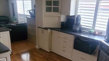 A kitchen with white cabinets, a black countertop, and a wooden floor.
