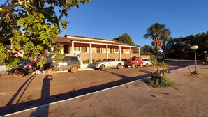 A building with a tiled roof and a parking lot with several vehicles. - POUSADA BEIRA RIO - JALAPÃO (Ponte Alta do Tocantins)