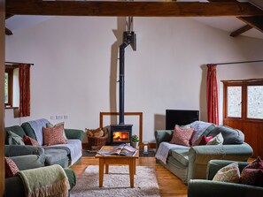 A cozy living room with two sofas, a fireplace, a television, and a window with curtains. - Well equipped four bedroom property with plenty of space in a rural location. (Bideford)
