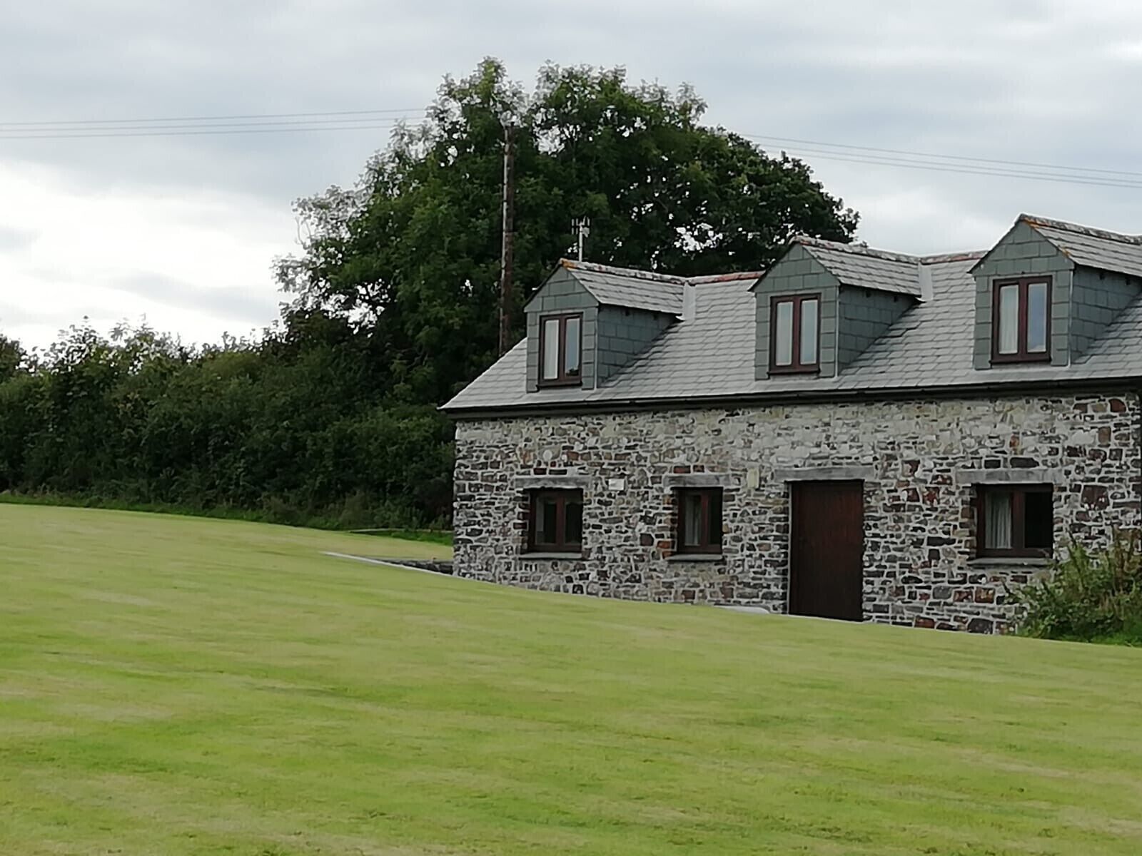 A stone building with a sloped roof, multiple windows, and a door.