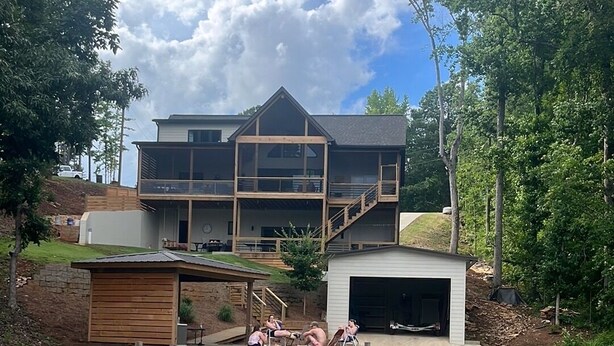 A lakeside house with a dock, a covered deck, and a garage.