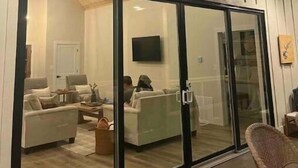 A modern interior with a large sliding glass door leading to a living area with a sofa and a television.