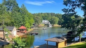 A lakeside property with a dock, a small pavilion, and a house in the background.