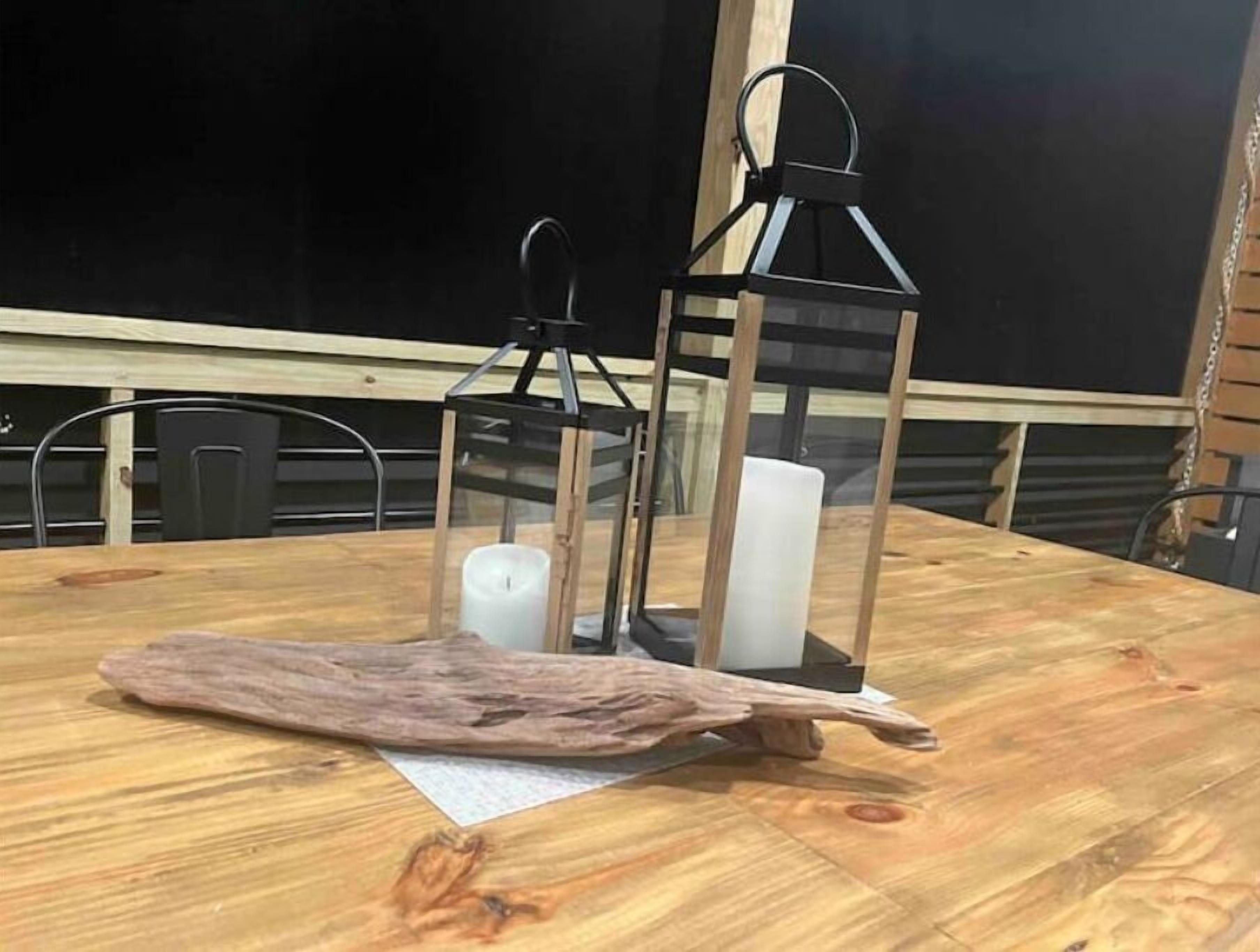 A wooden table with a candle and two lanterns.