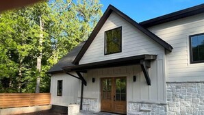 A modern house with a stone exterior, a wooden door, and a stone staircase leading to the front door.