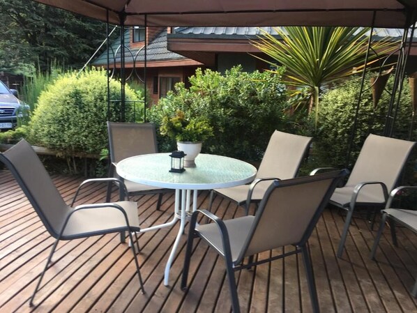 A round table with four chairs, surrounded by a wooden deck.