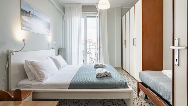 Ein Hotelzimmer mit Bett, Schreibtisch, Kleiderschrank und Blick auf die Stadt.