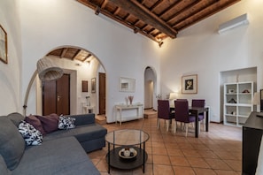 A living room with a sofa, a round coffee table, a dining area with chairs, and a white console table.
