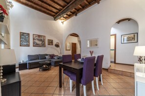 A dining area with a table and chairs, a sofa, and a ceiling with exposed beams.