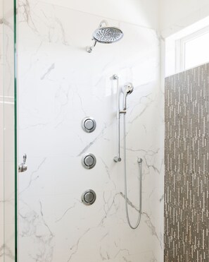 Eine moderne Dusche mit Handbrause, Bedienfeld an der Wand und Regendusche.