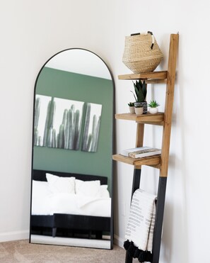 Ein Schlafzimmer mit einem Bett, einem Spiegel und einem Holzboden mit Dekorationen.