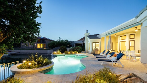 A swimming pool with lounge chairs and a well-lit patio area. - Gorgeous Lakefront Home with Infinity Pool & Hot Tub, Sleeps Up to 12 (Glendale)