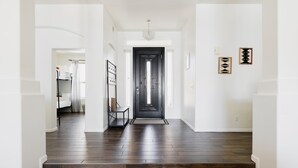 A hallway with dark wooden flooring, white walls, and a black door at the end. - Gorgeous Lakefront Home with Infinity Pool & Hot Tub, Sleeps Up to 12 (Glendale)