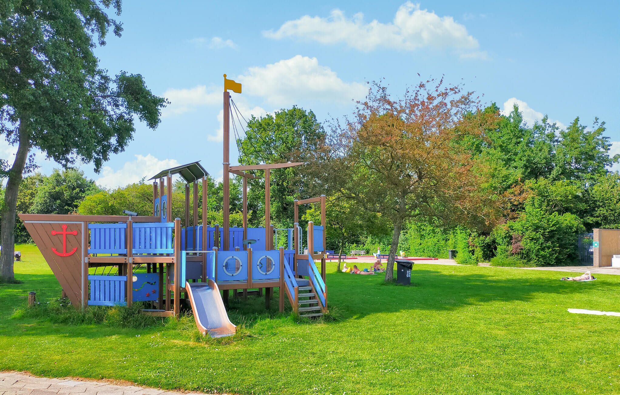A playground with a slide, climbing structures, and a flagpole.