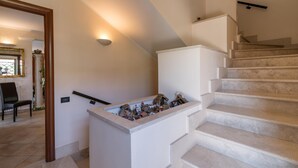 Una escalera con barandilla blanca y peldaños color beige, que conduce a un rellano con una pequeña decoración.