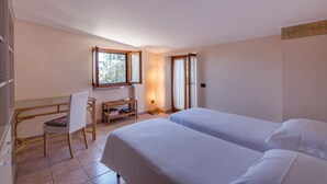Una habitación de hotel con dos camas, un escritorio con una silla, una ventana y una lámpara.