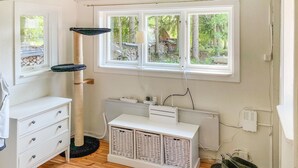 A room with a white dresser, a cat tree, a radiator, and a window with a view of trees. - Cozy home in örebro with WiFi (Örebro)