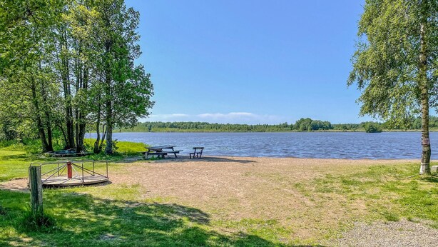 A lakeside picnic area with benches and a picnic table, surrounded by trees and a clear view of the lake. - Cozy home in örebro with WiFi (Örebro)
