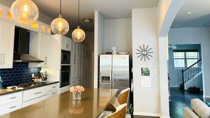 A modern kitchen with a central island, stainless steel appliances, and pendant lighting.