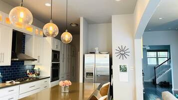 Una cocina moderna con una isla central, electrodomésticos de acero inoxidable e iluminación colgante.