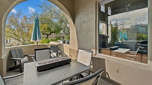 Una terrazza esterna con tavolo, sedie e ombrellone.