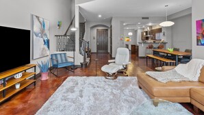 Un soggiorno moderno con televisore, posti a sedere e una scala che conduce a una sala da pranzo.
