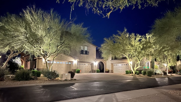 Una casa residenziale con garage, vialetto e giardino curato di sera.