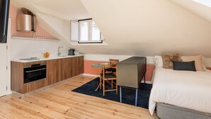 Een compact appartement in moderne stijl, met een keuken, een eethoek en een slaapkamer.