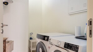 Une buanderie équipée d’un lave-linge à chargement frontal, d’une petite table et d’un évier.