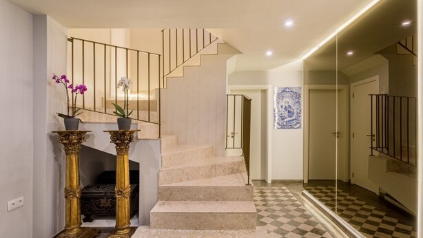 A staircase with a checkered floor leading to a room with a large mirror and a blue artwork on the wall. - JOIVY  Homey Suite near Rossio Square (Lisboa)