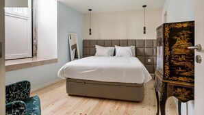Een slaapkamer met een bed, een kaptafel, een stoel en een raam.
