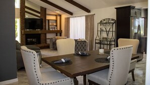 A modern living room with a dining area, featuring a fireplace, a television, and a glass display cabinet. -  Private  Pool Home 
Nestled on the Golf Course (North Fort Myers)
