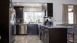 A modern kitchen with dark cabinetry, stainless steel appliances, and a marble countertop. -  Private  Pool Home 
Nestled on the Golf Course (North Fort Myers)