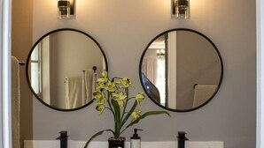 A bathroom with two round mirrors, a sink, and a vanity with drawers. -  Private  Pool Home 
Nestled on the Golf Course (North Fort Myers)