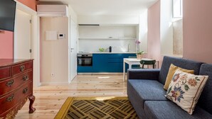 A modern apartment with a kitchen, a living area with a sofa and a coffee table, and a wooden floor.