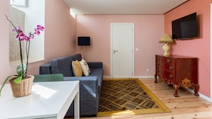 A living room with a sofa, a small table, a TV, a cabinet, and a patterned rug.