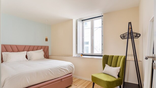 A bedroom with a bed, a window, a chair, and a ladder.