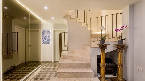 A staircase with a checkered floor leading to a landing with a decorative wall piece. - JOIVY Modern apt near Rossio Square (Lisboa)