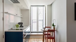 A compact kitchen with a dining area, a large window, and a potted plant. - JOIVY Modern apt near Rossio Square (Lisboa)
