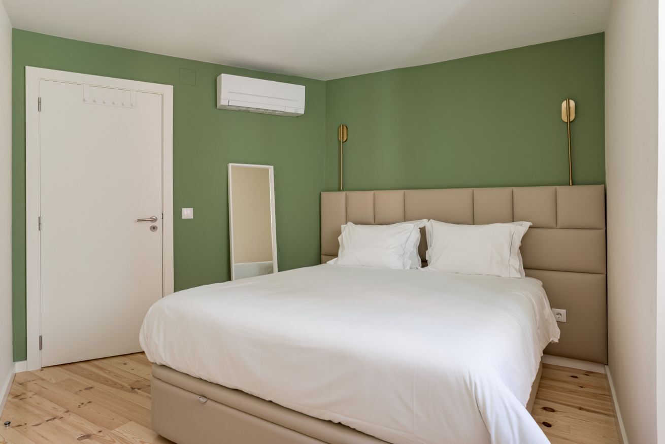 Une chambre à coucher avec un lit, une porte, un appareil de climatisation et un miroir.