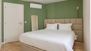 A bedroom with a bed, a door, an air conditioning unit, and a mirror. - JOIVY Modern apt near Rossio Square (Lisboa)