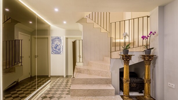 Un escalier dont les marches sont recouvertes d’un carrelage à motifs géométriques, menant à un palier.