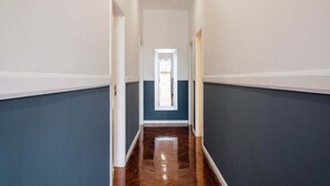 Un couloir aux murs bleu foncé, aux boiseries blanches et au plancher en bois.