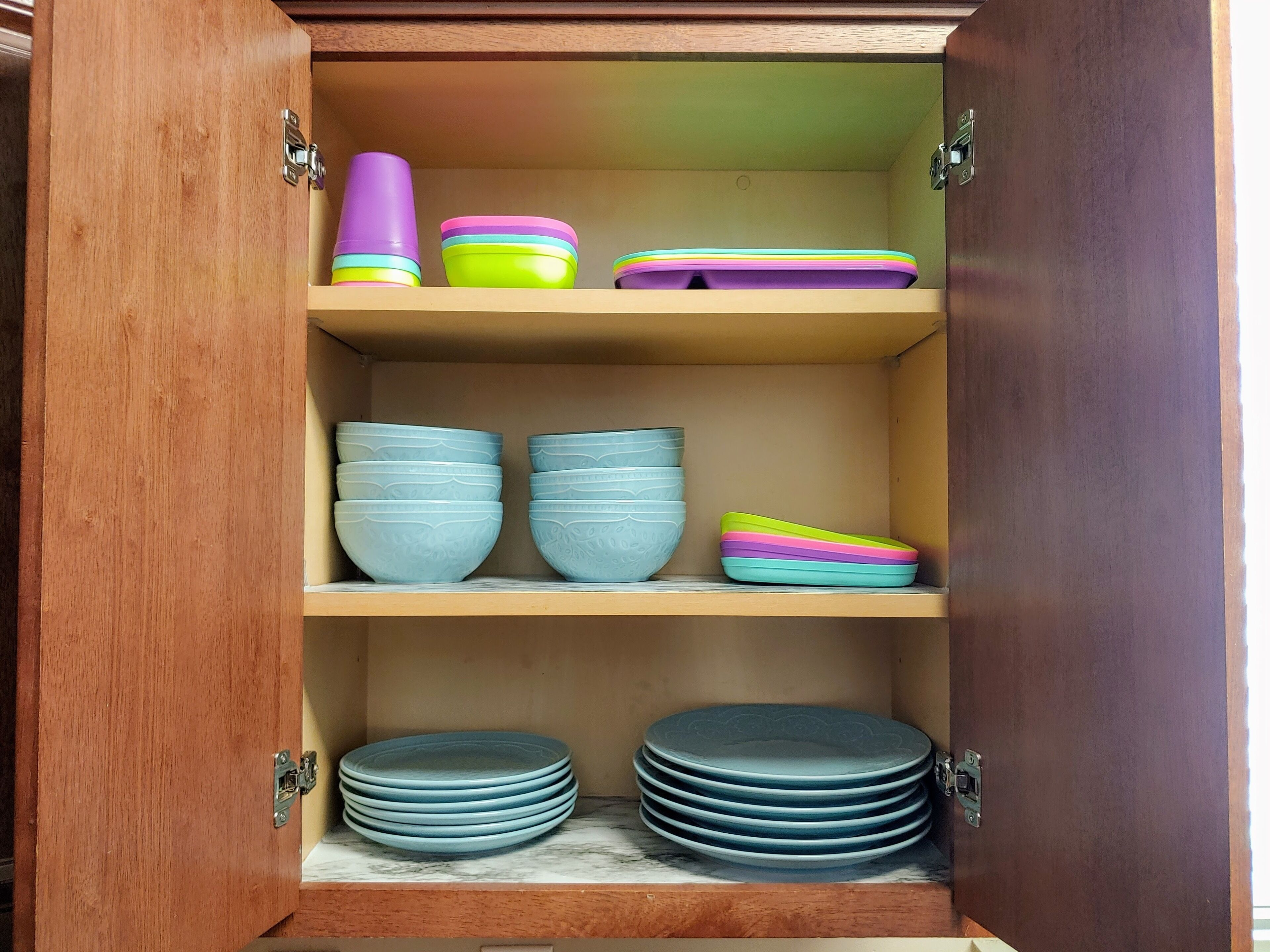 A wooden cabinet with shelves holding various kitchenware items.