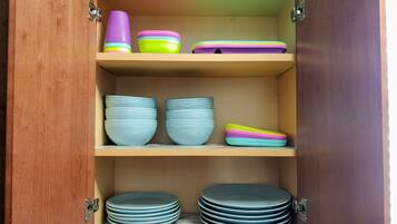 A wooden cabinet with shelves holding various kitchenware items.